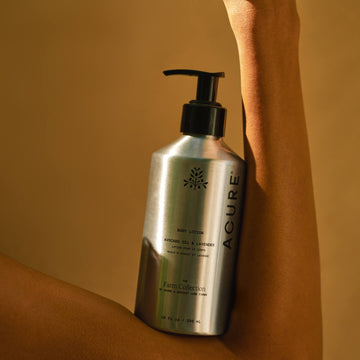 Acure body lotion bottle held against a beige background